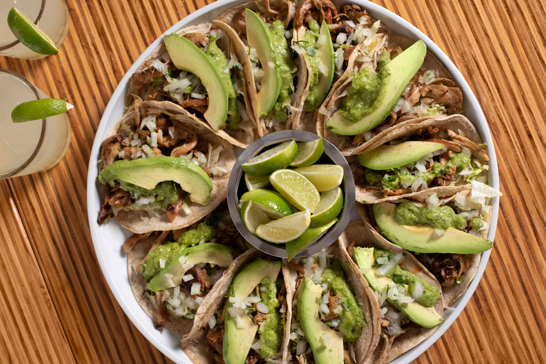Photo of a plate of tacos with avocado and limes